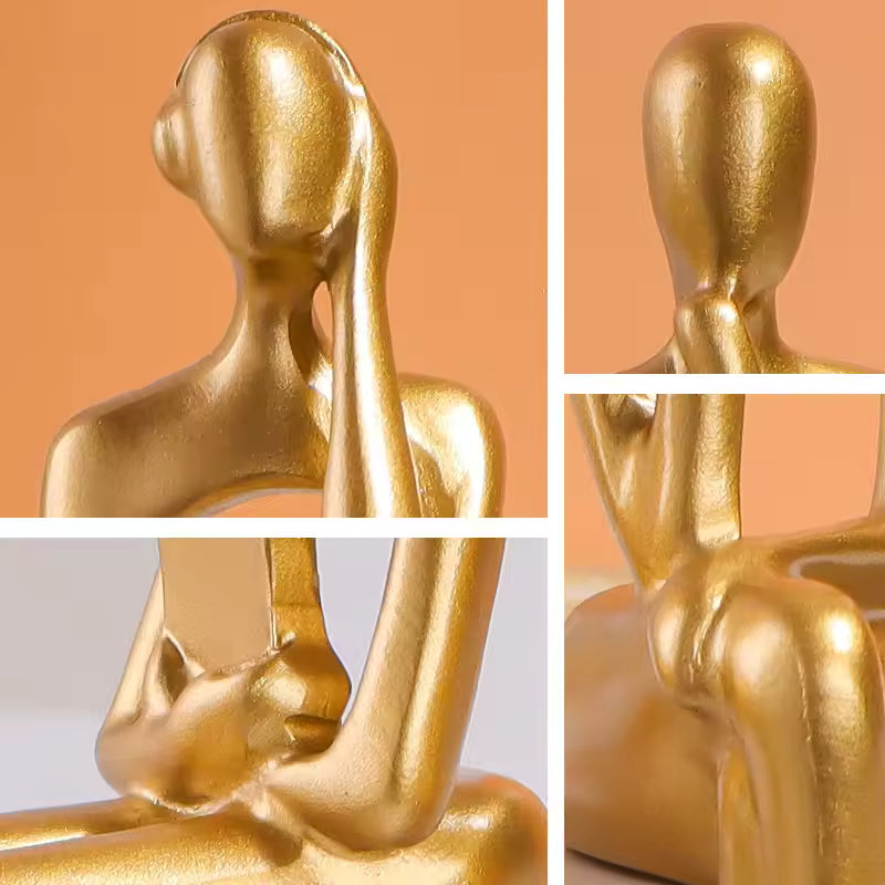 Gold-colored sculpture of a seated figure against an orange background